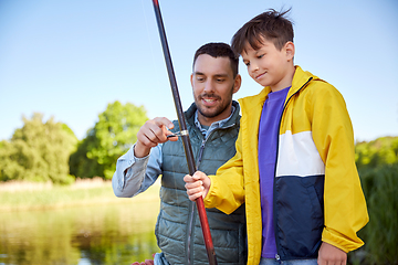 Image showing happy smiling father and son fishing on river