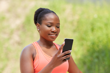 Image showing sporty african woman using smartphone outdoors