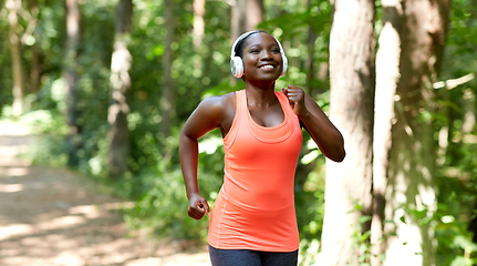 Image showing happy african woman in headphones running in park