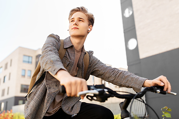 Image showing teenage boy with earphones and bag riding bicycle