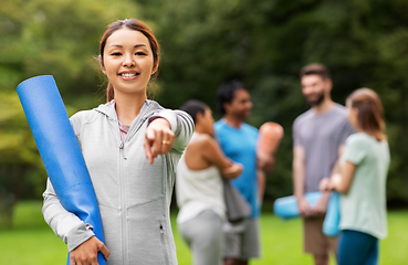 Image showing woman with yoga mat pointing finger to camera