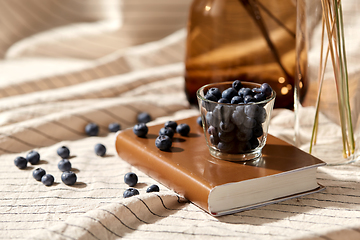 Image showing cup of blueberry, book and dried flowers in vases