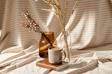 Image showing cup of coffee on book and dried flowers in vases