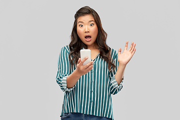 Image showing surprised asian woman using smartphone