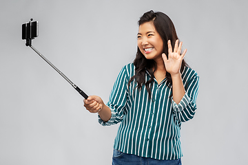 Image showing happy asian woman taking selfie and waving hand