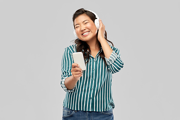 Image showing happy asian woman in headphones listening to music