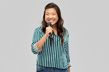 Image showing happy asian woman with microphone singing