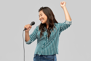 Image showing happy asian woman with microphone singing