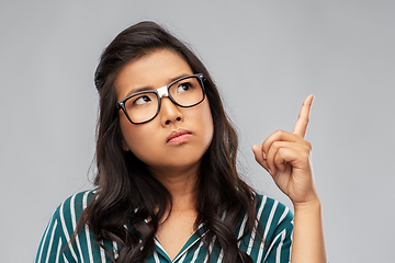 Image showing worried asian woman in glasses pointing finger up