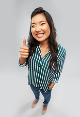 Image showing happy asian woman showing thumbs up over grey