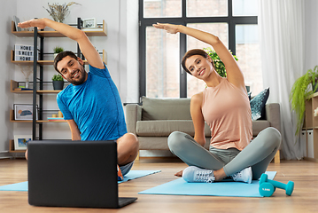 Image showing happy couple with laptop exercising at home