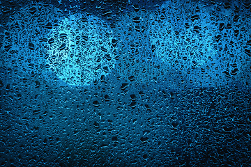 Image showing Blue bokeh lights behind a wet window