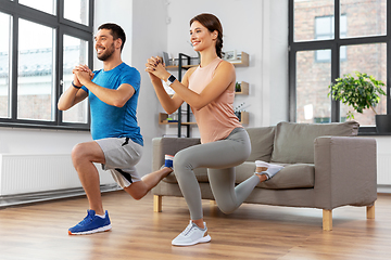 Image showing happy couple exercising and doing squats at home