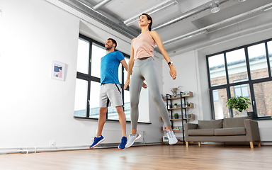 Image showing happy couple exercising and jumping at home