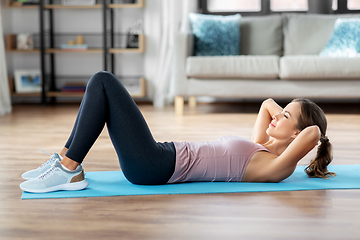 Image showing young woman exercising and doing sit-ups at home