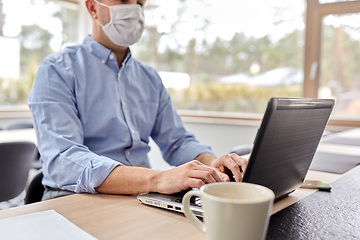 Image showing man in mask with laptop working at home office