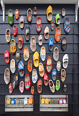 Image showing Many multicolored vintage Dutch Klomp shoes on black wood panel 