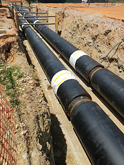 Image showing Laying heating pipes in a trench at construction site.