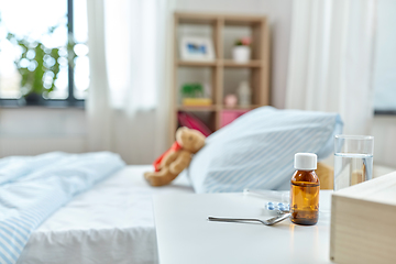 Image showing medicine on table and teddy bear in bed at home