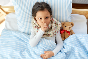 Image showing sick coughing girl lying in bed at home