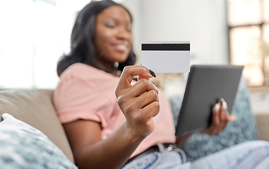 Image showing happy woman with tablet pc and credit card at home