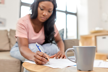 Image showing african woman with papers and calculator at home