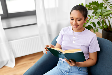 Image showing happy african american woman reading book at home