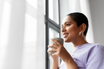 Image showing happy woman with coffee looking out of window