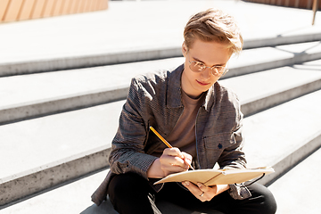 Image showing young man with notebook or sketchbook in city