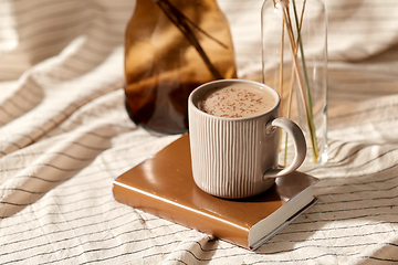 Image showing cup of coffee on book and dried flowers in vases