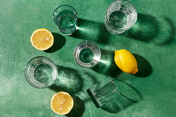 Image showing glasses with water and lemons on green background