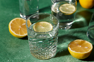 Image showing glasses with water and lemons on green background