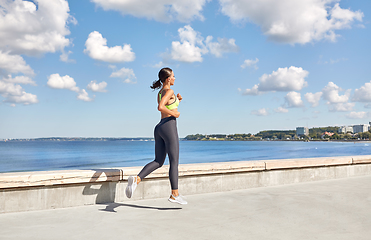 Image showing young woman running along sea promenade