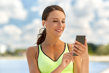 Image showing woman with earphones and smartphone doing sports