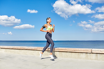 Image showing woman with headphones and smartphone running