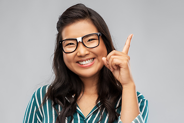 Image showing happy asian woman in glasses pointing finger up