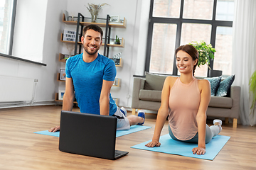 Image showing happy couple with laptop exercising at home