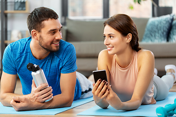 Image showing happy couple with smartphone after sports at home