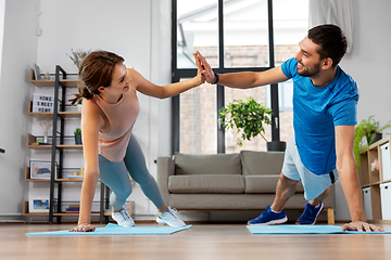 Image showing happy couple make high five in side plank at home