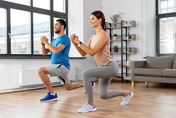 Image showing happy couple exercising and doing squats at home