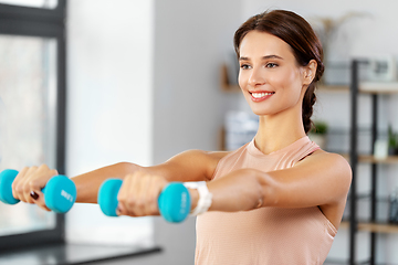 Image showing happy woman with dumbbells exercising at home