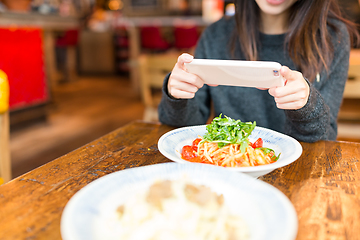 Image showing Woman taking photo on dish in coffee shop