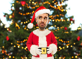 Image showing sad man in santa claus costume over christmas tree