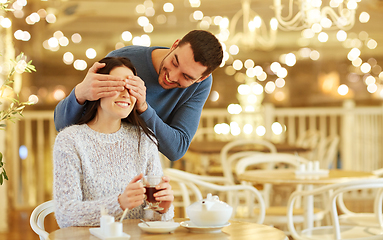 Image showing happy couple drinking tea at cafe over lights