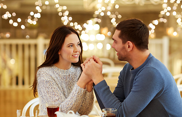 Image showing happy couple with tea holding hands at restaurant