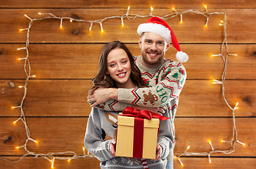 Image showing happy couple in christmas sweaters with gift box