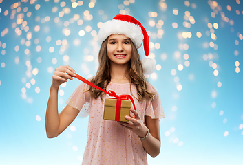 Image showing teenage girl in santa hat opening christmas gift