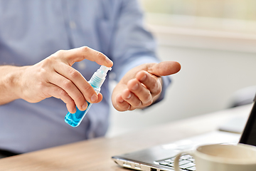 Image showing man using hand sanitizer at home office