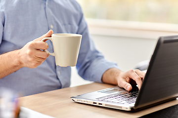 Image showing man with laptop drinking coffee at home office