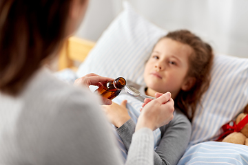 Image showing mother pouring cough syrup for sick daughter